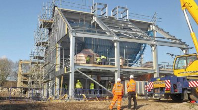 Copper tanks are lowered into position through holes in the steelwork
