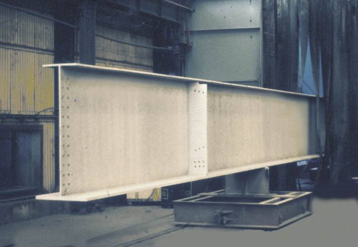 Steel beam emerging from an automatic blast cleaning unit