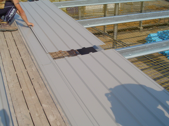 Liner sheet installation progressing into the span of the purlins