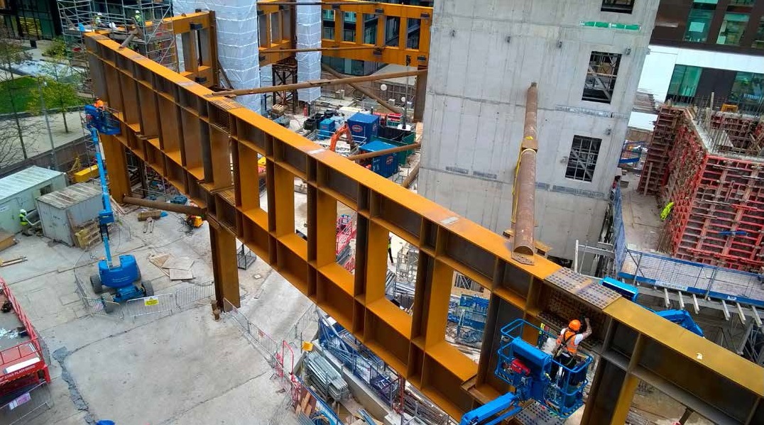Truss sections are bolted together, while (at the top of the picture) welding is undertaken inside enclosures