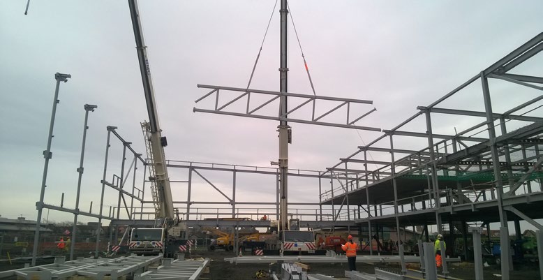 One of the five trusses that form the central zone is lifted into place