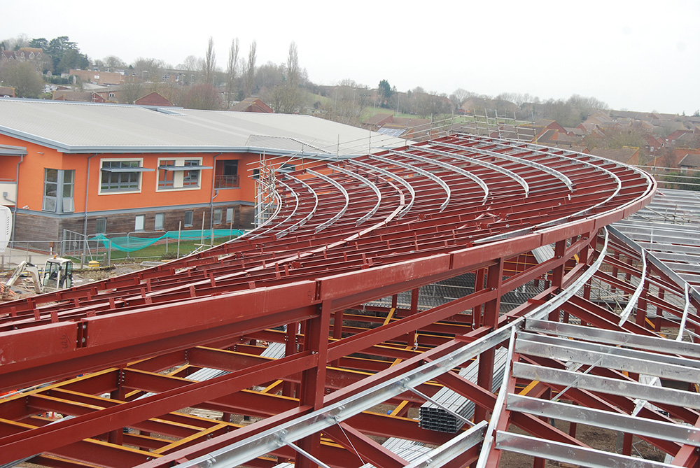 A large sloping curved roof fits into the site’s topography